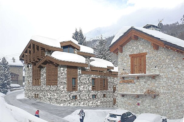 A stone building with a wooden roof is covered in snow