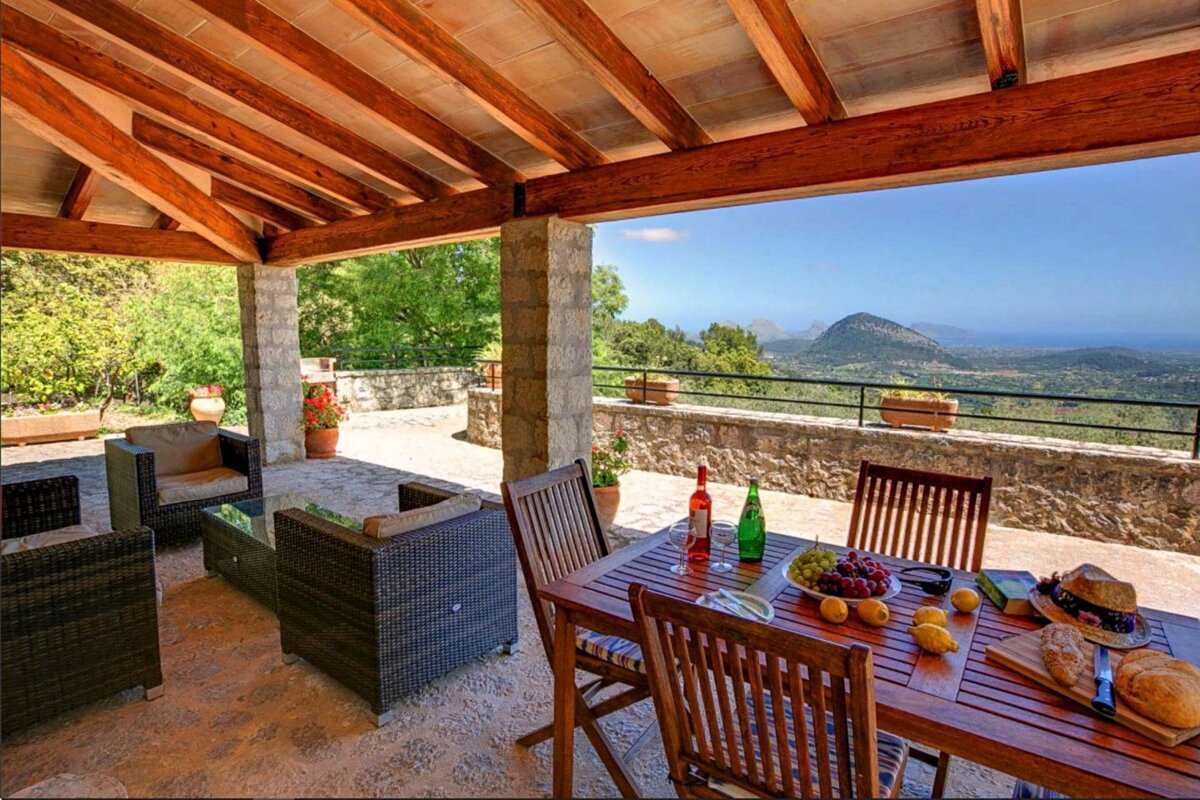 A patio with a table and chairs and a bottle of wine on it