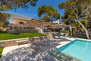 A swimming pool with chairs and umbrellas in front of a house