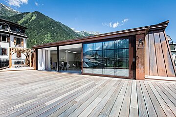 A wooden deck with a sliding glass door and mountains in the background