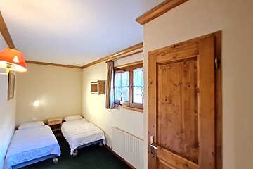 A bedroom with two beds and a wooden door