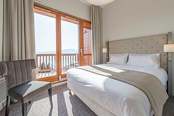 A hotel room with a large bed and a chair