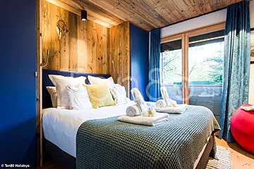 A bedroom with blue walls and a bed with towels on it