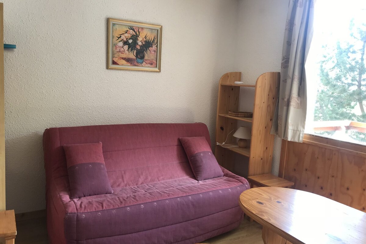 A living room with a pink couch and a picture on the wall above it