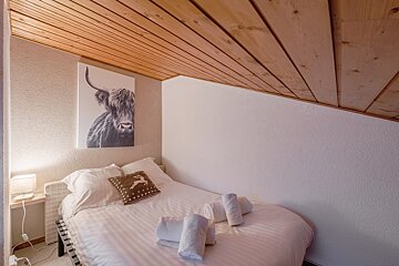 A bedroom with a bed and a dresser with a basket on it