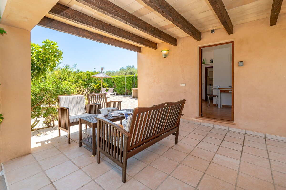 A patio with a couch and chairs under a wooden roof