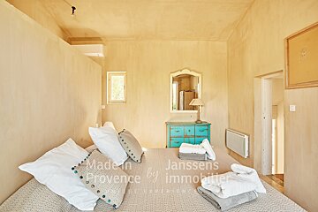 A bedroom with a bed and a dresser made in provence by janssens immobilier