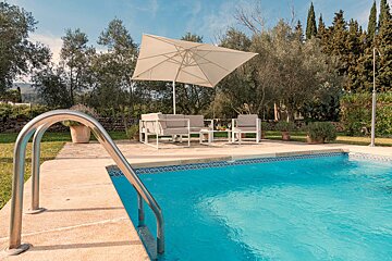 A swimming pool with a white umbrella in the background