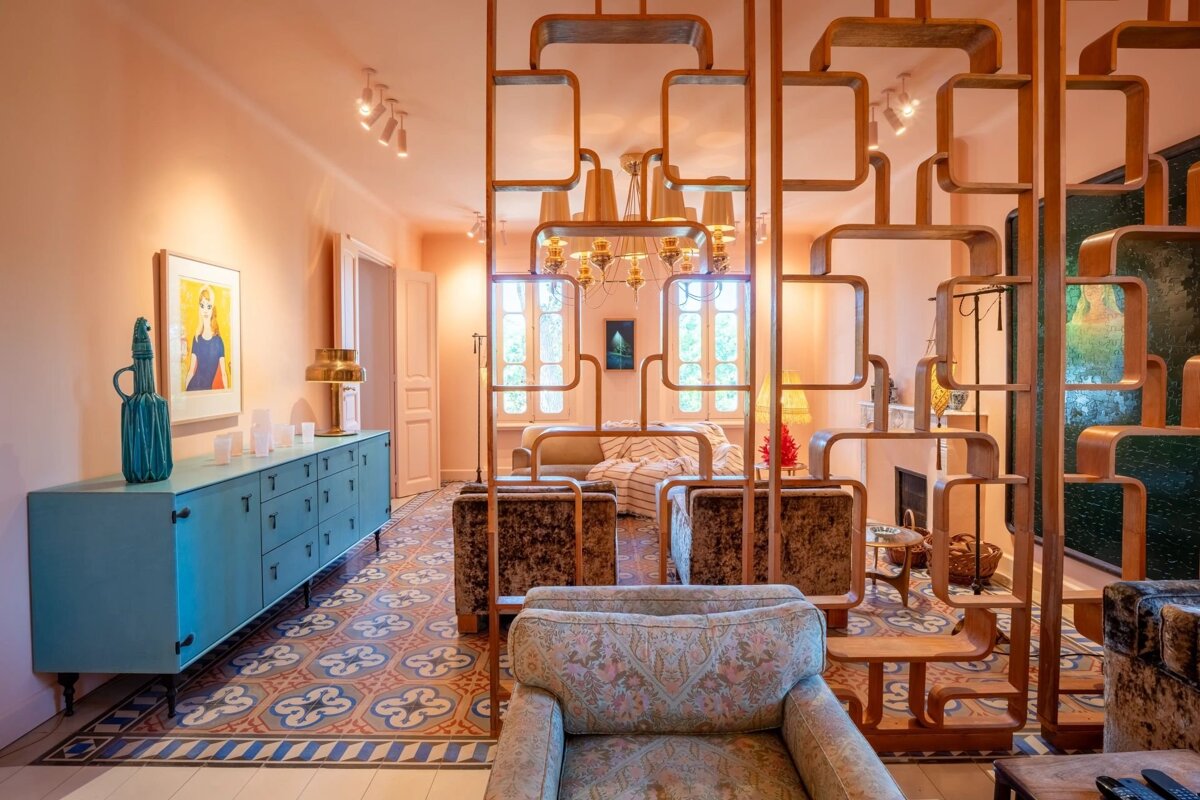 Retro living room featuring a geometric wooden room divider, patterned tile floor, peach walls, and a teal credenza.