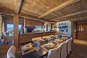 A dining room with a table and chairs and a painting on the wall