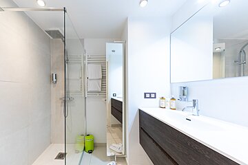 A bathroom with a walk in shower and a sink