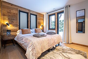 A bedroom with a large bed and two windows