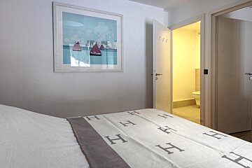 A bed with a blanket that has the letter h on it