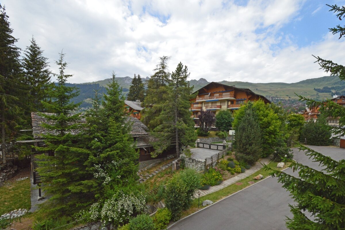 A large building in the middle of a forest with mountains in the background