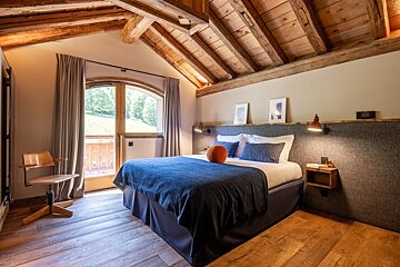 A bedroom with a large bed and a chair