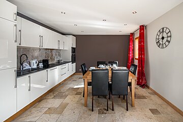 A kitchen with a table and chairs and a clock on the wall