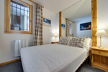 A bedroom with a large mirror and a bed