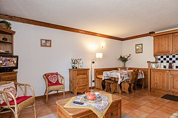 A living room with a table and chairs and a tv