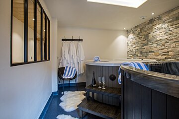 A bottle of champagne sits on a table next to a hot tub