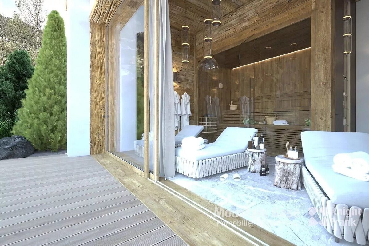 Luxurious wooden spa interior with glass doors leading to an outdoor deck and evergreen trees. Features recliners, robes, and a sauna.