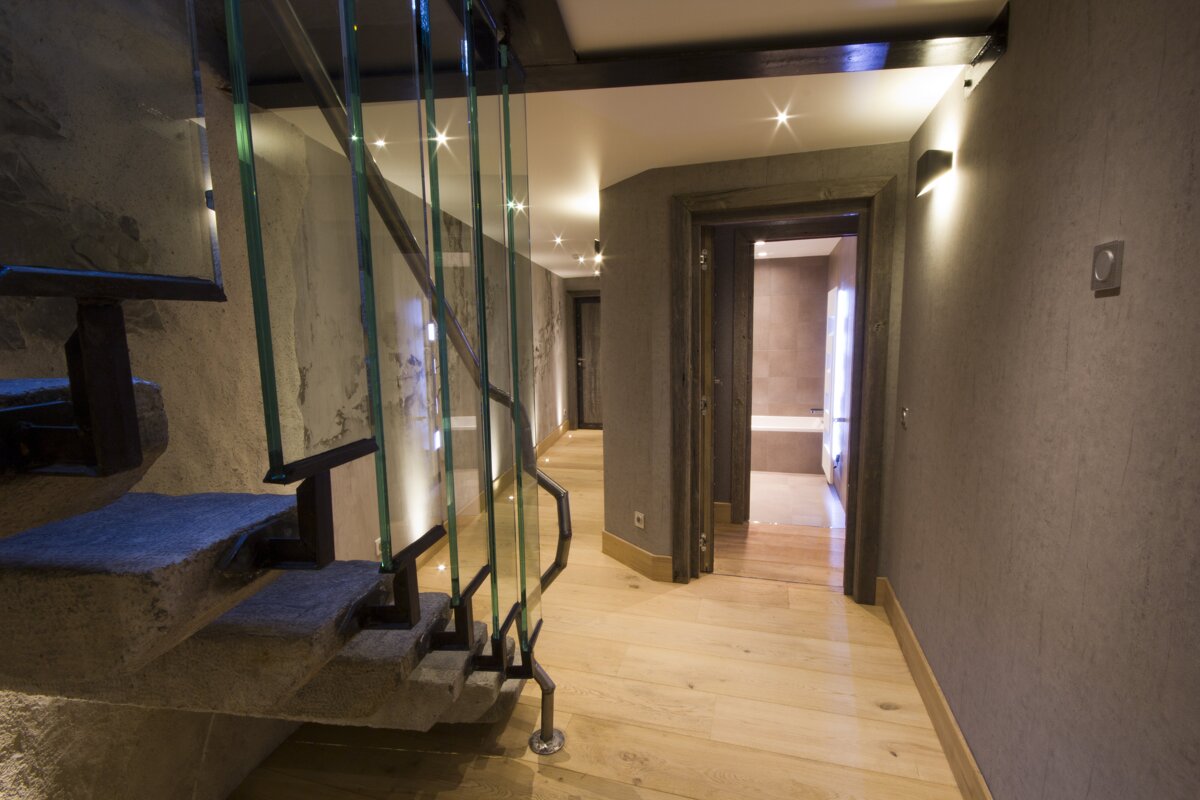 A hallway with a staircase and a glass railing
