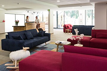 A man and a woman are standing at a counter in a lobby