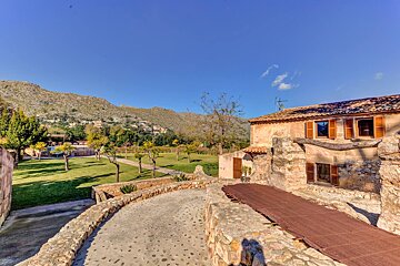 A stone walkway leading to a house with a mountain in the background