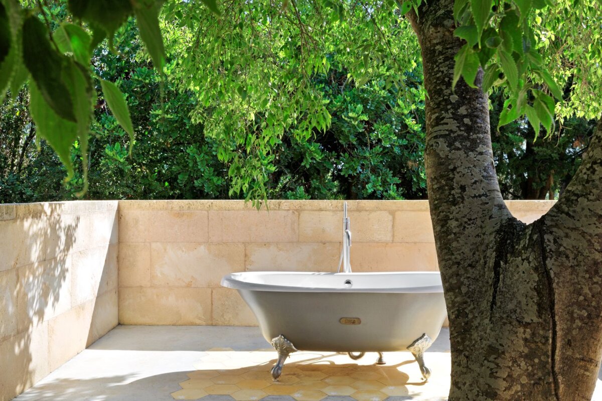 A bathtub is surrounded by trees in a bathroom