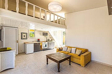 A living room with a yellow couch and a wooden table