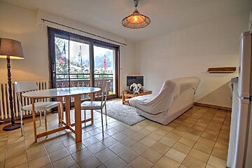 An open-concept apartment with a dining area, a living space, sliding glass doors to a balcony, and tile flooring.