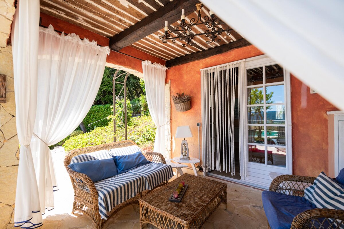 A porch with wicker furniture and white curtains