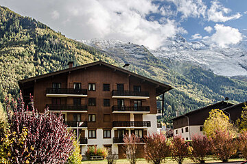 A building with a mountain in the background is surrounded by trees