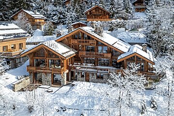 Stunning wooden chalets blanketed in fresh snow on a winter mountainside, surrounded by frosty trees.
