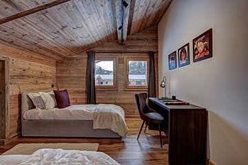 A bedroom with two beds and a desk with pictures on the wall