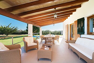 A large swimming pool is surrounded by lawn chairs and an umbrella