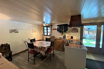 A kitchen with a table and chairs and a flat screen tv