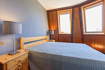A bedroom with a bed a nightstand and a lamp