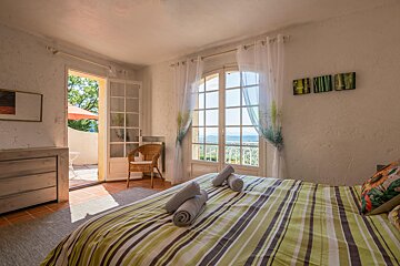 A bedroom with a striped bed and a chair