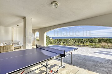 A ping pong table on a patio with a view of the ocean