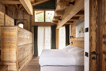 A bedroom with wooden walls and a bed with white sheets