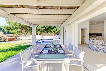 A table and chairs on a patio with a pool in the background