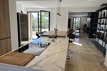 A kitchen with a marble counter top and a stove top oven