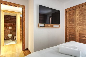 A bedroom with a flat screen tv above the bed