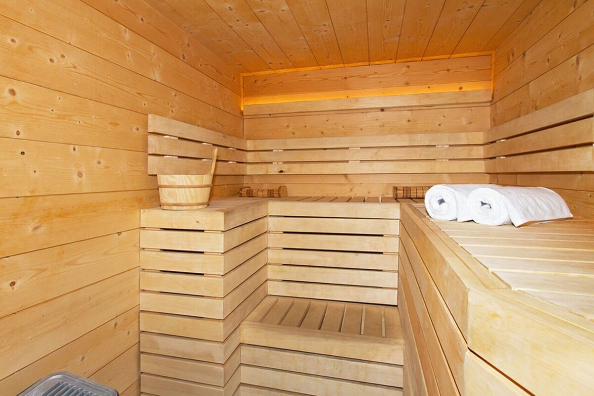 A wooden sauna with a bucket and towels on the benches