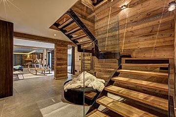 A wooden staircase with a glass railing in a house
