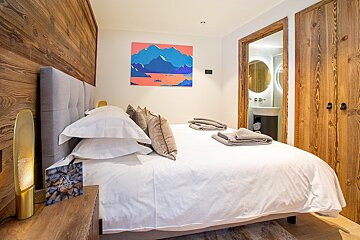 A bedroom with a painting on the wall above the bed