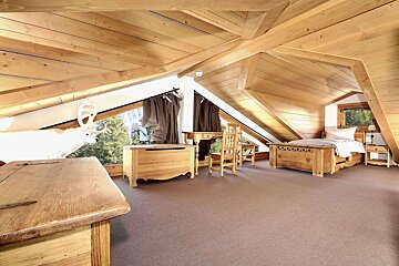 An attic bedroom with two beds and a desk