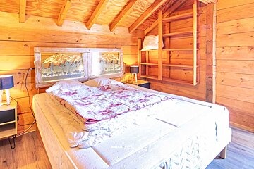 A bed in a wooden cabin with a window that says chalet