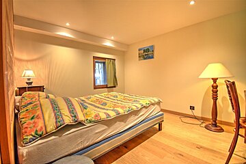 A bedroom with a painting on the wall above the bed