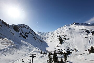 The sun is shining brightly on the snowy mountains